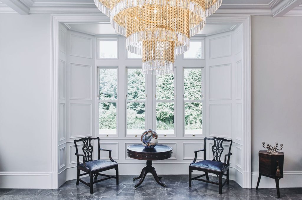 Traditional box sash window in a traditional house with a chandelier and black table and chairs Infront of the window